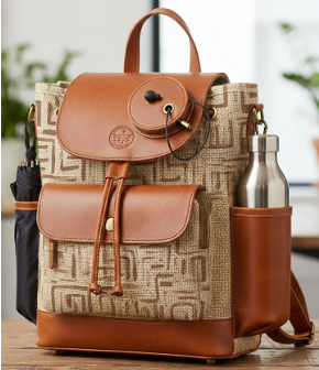 Detail of woven jute backpack with cognac leather flap and brass buckle, geometric block-print pattern visible on body